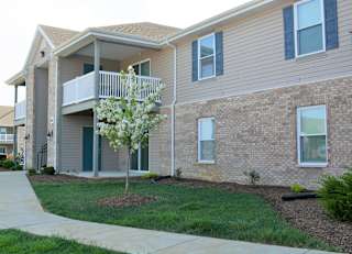 a building with a balcony and a tree in front of it at Hawthorne Properties in Lafayette, IN 47905
