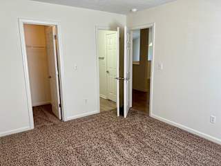 an empty bedroom with three doors and a carpeted floor at Shenandoah Properties in Lafayette, IN 47905