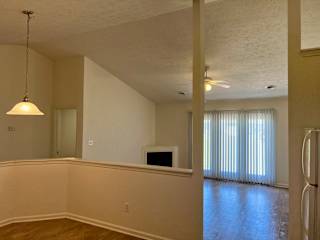 A room with a ceiling fan and a refrigerator.