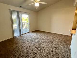 an empty living room with a ceiling fan and a balcony at Shenandoah Properties in Lafayette, IN 47905