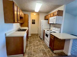 an empty kitchen with white appliances and wooden cabinets at Shenandoah Properties in Lafayette, IN 47905