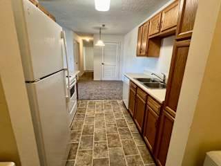 a kitchen with white appliances and wooden cabinets at Shenandoah Properties in Lafayette, IN 47905