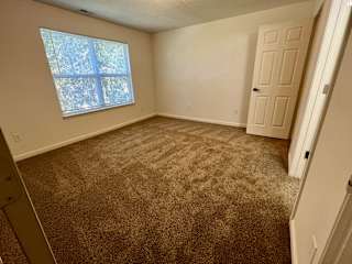 an empty bedroom with carpet and a window at Shenandoah Properties in Lafayette, IN 47905