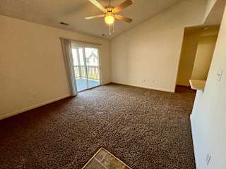 an empty living room with carpet and a ceiling fan at Shenandoah Properties in Lafayette, IN 47905