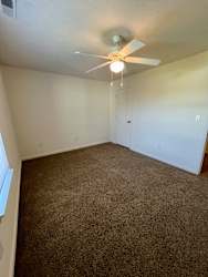 an empty living room with carpet and a ceiling fan at Shenandoah Properties in Lafayette, IN 47905
