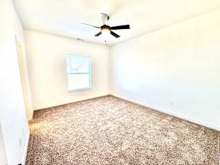 A room with a ceiling fan and carpeted floor.at Concord Crossing, Indiana, 47909