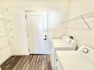 A white door is in a laundry room with a washer and dryer.at Concord Crossing, Lafayette, 47909
