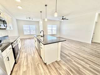 A kitchen with white cabinets and a black countertop.at Concord Crossing, Lafayette Indiana