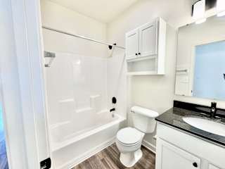 A white toilet sits in a small bathroom with a sink and a shower.at Concord Crossing, Lafayette, IN 47909