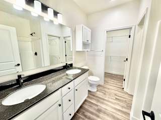 A bathroom with a sink, mirror, toilet and cupboard.at Concord Crossing, Indiana