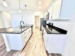 A modern kitchen with white cabinets and black countertops.at Concord Crossing, Lafayette Indiana
