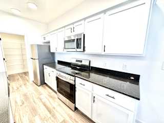 A kitchen with white cabinets and black countertops.at Concord Crossing, Indiana