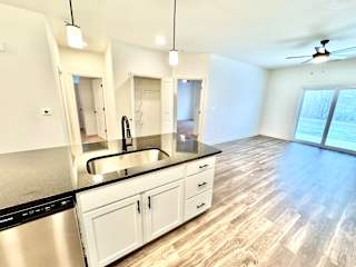 A modern kitchen with a stainless steel sink and black countertop.at Concord Crossing, Lafayette, IN