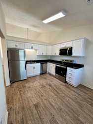 A kitchen with a refrigerator, microwave, and oven.