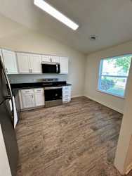A kitchen with white cabinets and black appliances.