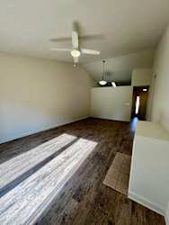 A room with a ceiling fan and wooden flooring.