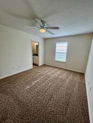 A room with a ceiling fan and carpeted floor.