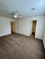 A room with a ceiling fan and carpeted floor.