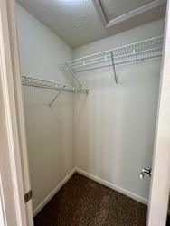 A small, empty walk-in closet with a carpeted floor.