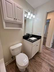 A white toilet sits in a bathroom with a sink and cabinet.