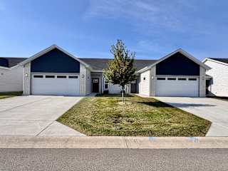 A large house with a garage and a tree in front.