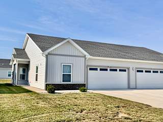 A two-car garage with a white house in the background.