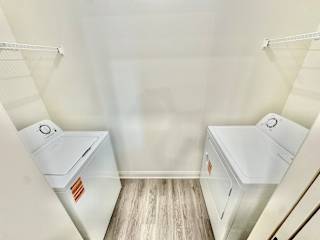 A white room with two washing machines and a wooden floor.