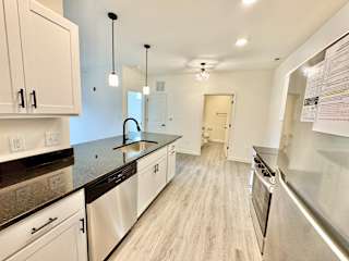 A kitchen with white cabinets and a black countertop.