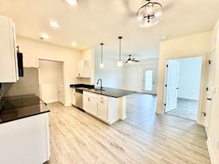 A kitchen with white cabinets and a black countertop.