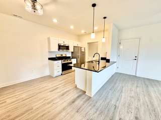 A kitchen with a black counter top and white cabinets.