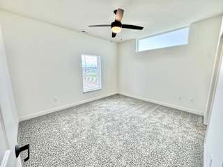 A room with a ceiling fan and carpeted floor.