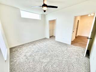 A room with a ceiling fan and carpeted floor.