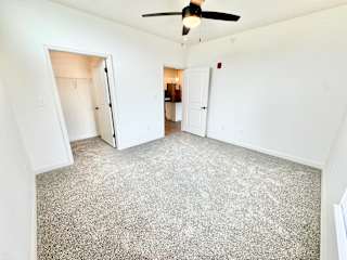 A room with a ceiling fan and carpeted floor.