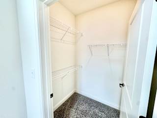 A white closet with a grey carpet and shelves.