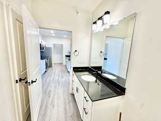 A bathroom with a sink, mirror, and a door.