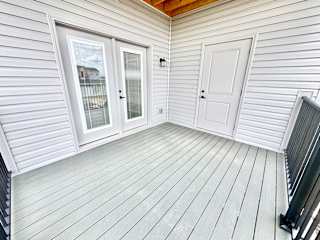 A white wooden deck with a sliding glass door and a white door.