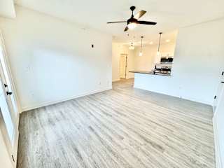 A spacious room with a ceiling fan and lighting fixtures.