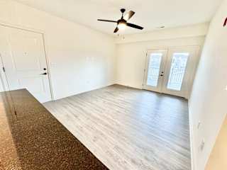 A room with a brown rug on the floor and a ceiling fan.