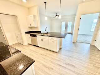 A kitchen with white cabinets and a black countertop.