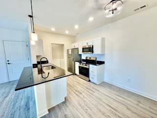 A kitchen with a black countertop and white cabinets.