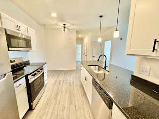 A modern kitchen with white cabinets and stainless steel appliances.