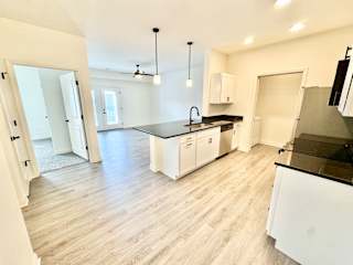 A kitchen with white cabinets and a black countertop.