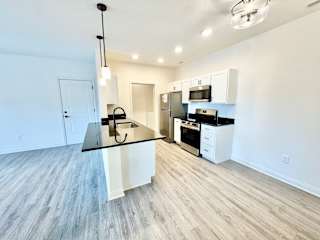 A kitchen with a black countertop and white cabinets.