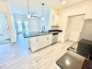 A kitchen with white cabinets and a black countertop.