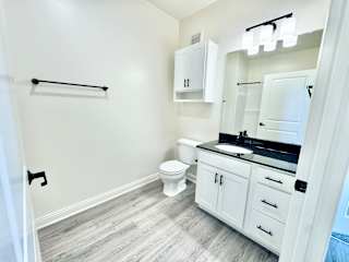 A bathroom with a toilet, sink, and a mirror.