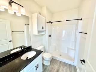 A bathroom with a black countertop and white fixtures.