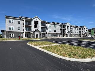 A large apartment complex with a parking lot in front.
