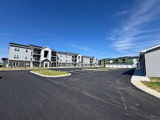 A large, modern apartment complex with a spacious parking lot in front.