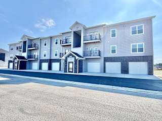 A modern apartment building with multiple balconies and garage doors.