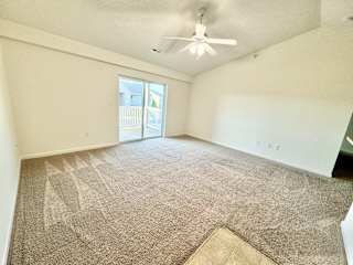 Cypress Upstairs Vaulted Living Room with Fan and Carpeted Floors, Glass Sliding Patio Door to Balcony at Hawthorne Properties in Lafayette, IN 47905